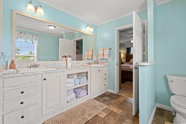 Ensuite bathroom featuring double vanity, stone finish flooring, and ornamental molding | Image 16