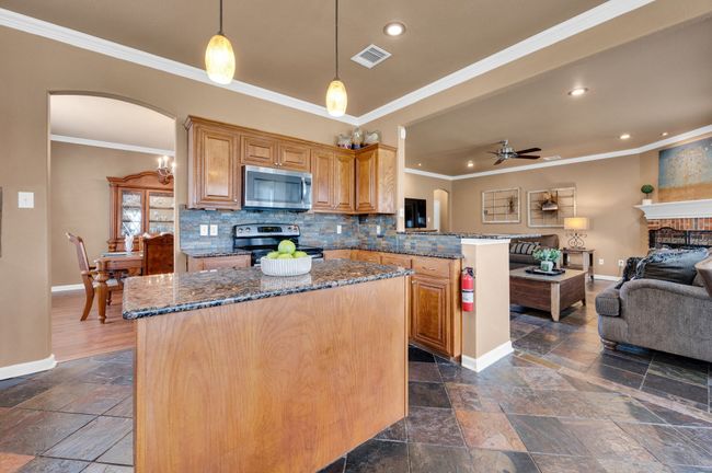 Kitchen with stainless steel appliances, stone tile floors, open floor plan, arched walkways, and a ceiling fan | Image 14