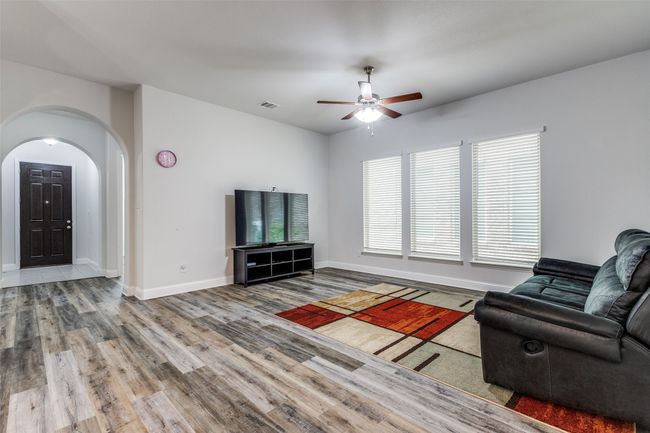Living area featuring visible vents, a ceiling fan, wood finished floors, arched walkways, and baseboards | Image 7