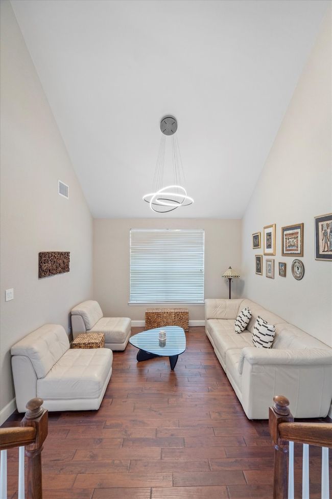 Living area featuring lofted ceiling, a chandelier, and wood finished floors | Image 9