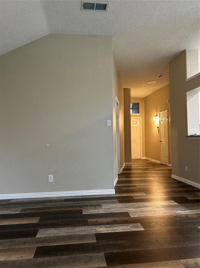 Unfurnished room featuring wood finished floors, a textured ceiling, and lofted ceiling | Image 6