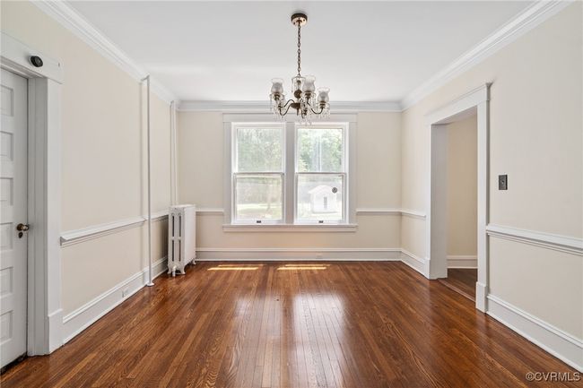 Dining area featuring radiator, a chandelier, hardwood / wood-flooring, baseboards, and crown molding | Image 15