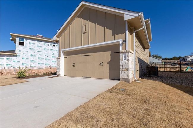 View of side of home with board and batten siding, a garage, concrete driveway, and stone siding | Image 5