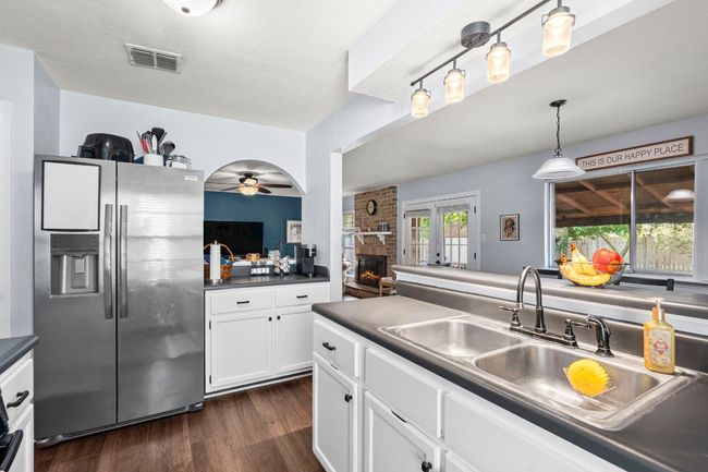 Kitchen featuring stainless steel refrigerator with ice dispenser, a sink, dark countertops, and ceiling fan | Image 14