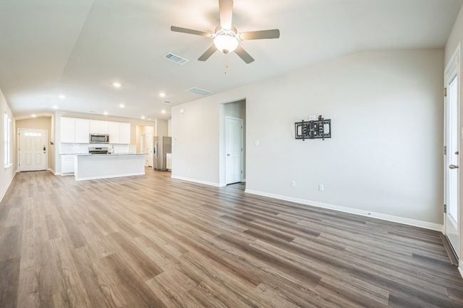 Unfurnished living room with vaulted ceiling, ceiling fan, recessed lighting, and light wood finished floors | Image 12