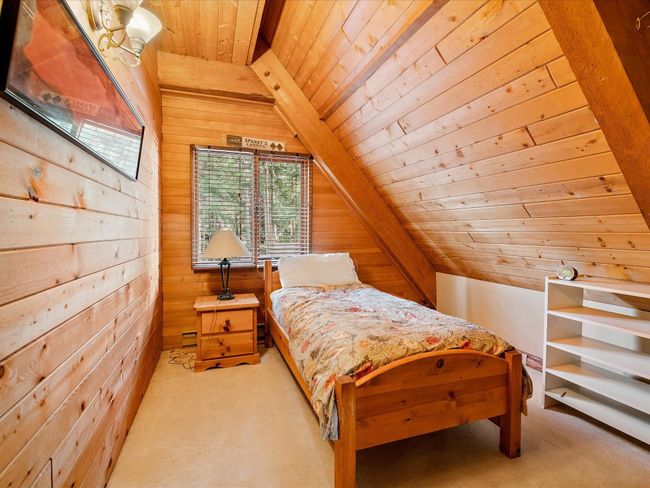 Bedroom with wood ceiling, light carpet, and wood walls | Image 25