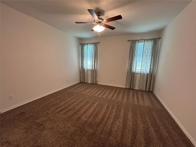 Spare room featuring plenty of natural light, a ceiling fan, dark colored carpet, and baseboards | Image 16