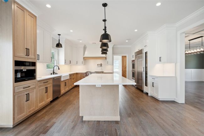 Kitchen featuring stainless steel appliances, custom range hood, light countertops, dark wood-style flooring, and crown molding | Image 8