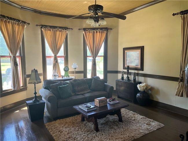 First floor cozy living room with wide baseboard and crown molding, wood ceiling, and hardwood / wood-style flooring | Image 17