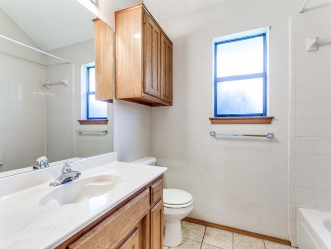 Bathroom featuring vanity, vaulted ceiling, tile patterned flooring, and washtub / shower combination | Image 15