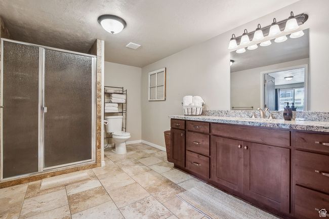 Bathroom with a shower stall, vanity, baseboards, toilet, and stone finish floor | Image 50
