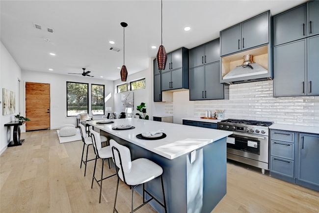 Kitchen with light hardwood / wood-style floors, a kitchen island, pendant lighting, a breakfast bar area, and stainless steel range with gas cooktop | Image 7