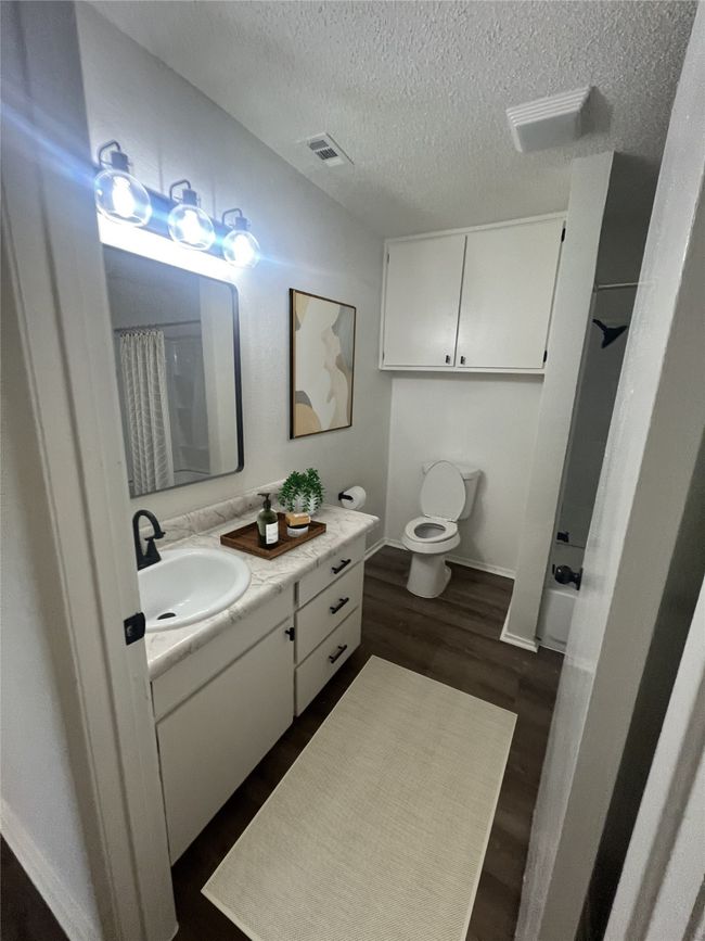 Bathroom with toilet, a textured ceiling, vanity, and a shower with shower curtain | Image 7