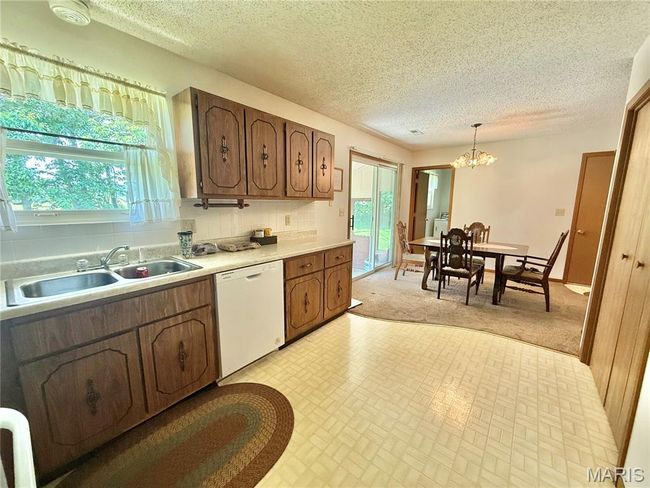 Kitchen with white dishwasher, healthy amount of natural light, backsplash, a chandelier, and a textured ceiling | Image 20