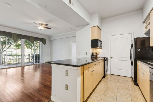 Kitchen featuring a peninsula, black appliances, a ceiling fan, open floor plan, and light brown​​‌​​​​‌​​‌‌​‌‌​​​‌‌​​‌‌​‌​​​​​‌ cabinetry | Image 14