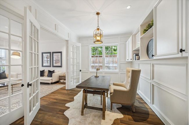 Home office/study with glass paneled French doors, paneled walls, cabinets and designer pendant. | Image 6