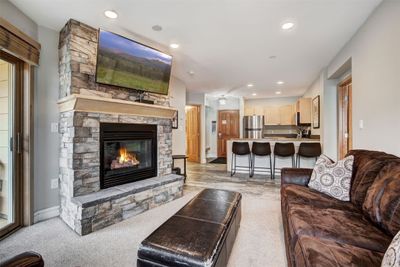 Living room with a stone fireplace and light carpet | Image 1