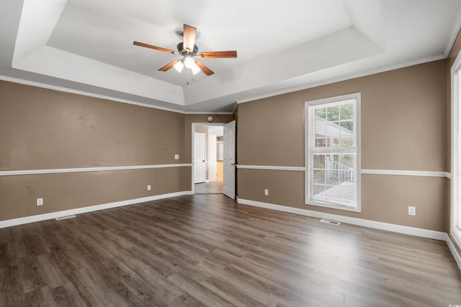 Unfurnished room featuring a tray ceiling, ceiling fan, wood finished floors, and ornamental molding | Image 21
