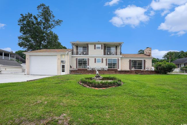 View of front of property with driveway, a balcony, a garage, a chimney, and brick siding | Image 34