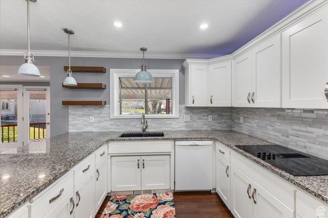 Kitchen with black electric stovetop, dishwasher, a sink, and ornamental molding | Image 5