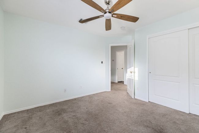 Bedroom with light colored carpet, a closet, baseboards, and ceiling fan | Image 23