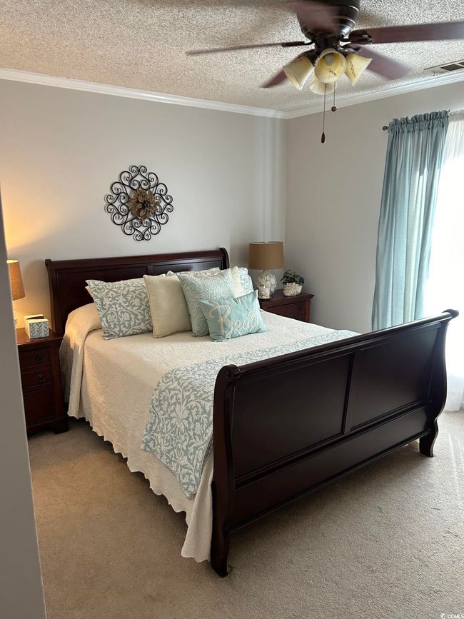 Bedroom featuring carpet flooring, ornamental molding, a textured ceiling, and a ceiling fan | Image 15