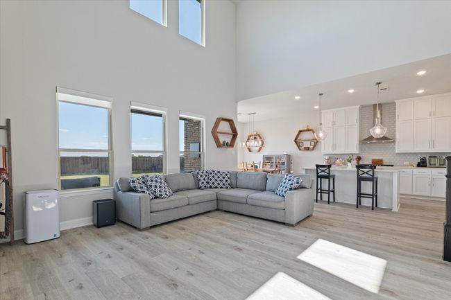 Living room with a high ceiling, plenty of natural light, light wood-style floors, recessed lighting, and baseboards | Image 16