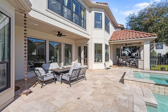 Covered backyard patio with an outdoor kitchen featuring a grill and sink, perfect for al fresco dining and entertaining. Ceiling fans ensure comfort throughout the year. | Image 48