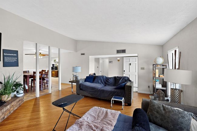 Living area with lofted ceiling, laminate wood finished floors, ceiling fan, and baseboards | Image 5