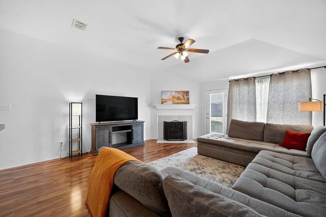 Living room with a ceiling fan, lofted ceiling, a fireplace, and wood finished floors | Image 9