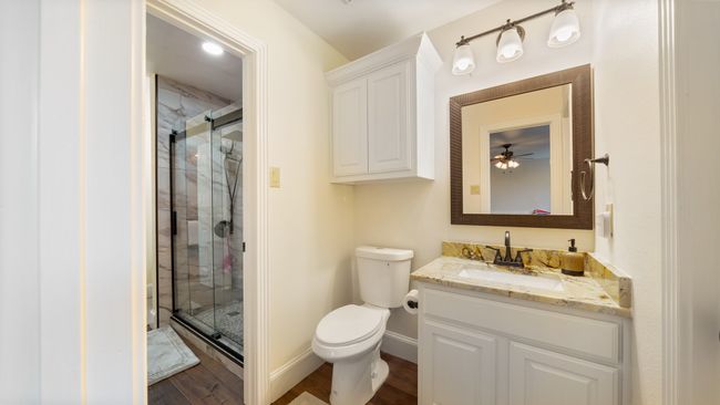 Bathroom with toilet, vanity, a shower stall, wood finished floors, and baseboards | Image 28