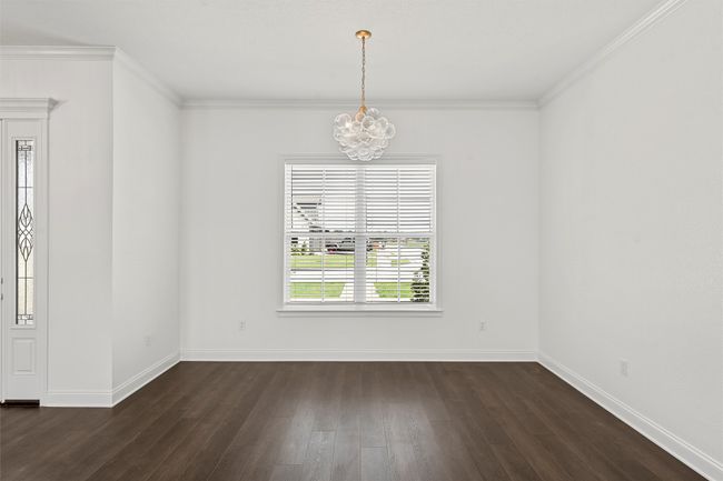 Empty room with a chandelier, dark wood finished floors, and crown molding | Image 31
