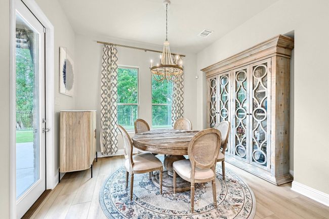 Dining room with light wood finished floors, a healthy amount of sunlight, an inviting chandelier, and visible vents | Image 15