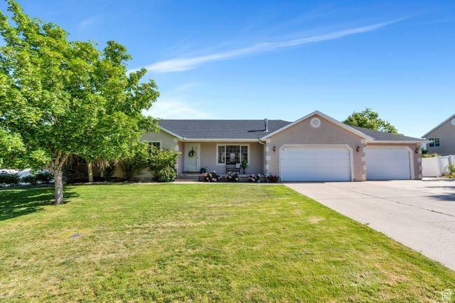 Ranch-style home featuring a garage, concrete driveway, and stucco siding | Image 31
