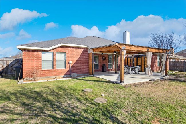 Spacious backyard patio with extended concrete and a charming pergola, perfect for outdoor relaxation and entertaining, plus ample enclosed storage for all your grilling appliances. | Image 25