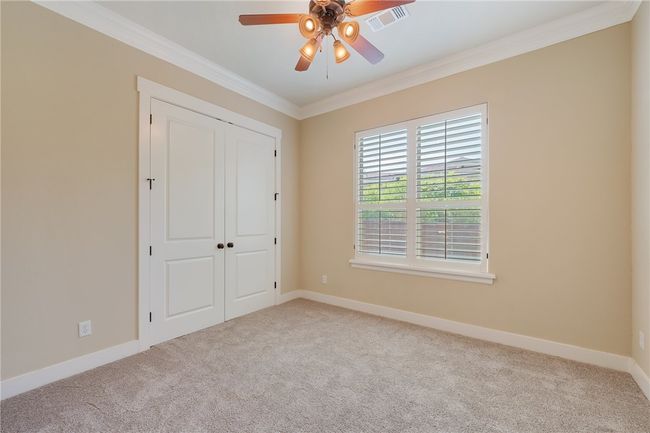 Unfurnished bedroom featuring ornamental molding, carpet floors, baseboards, a closet, and a ceiling fan | Image 13