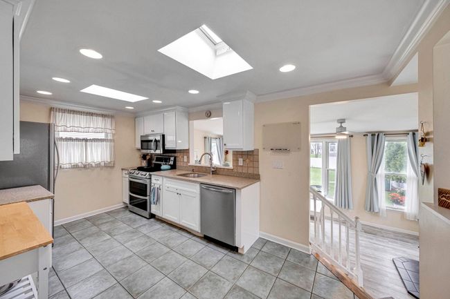 Kitchen featuring a sink, a skylight, stainless steel appliances, light countertops, and baseboards | Image 21