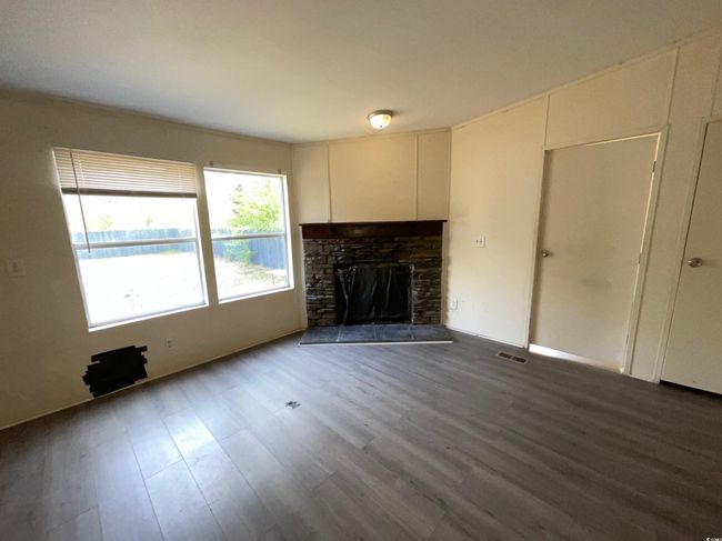 Unfurnished living room featuring wood finished floors and a fireplace | Image 6