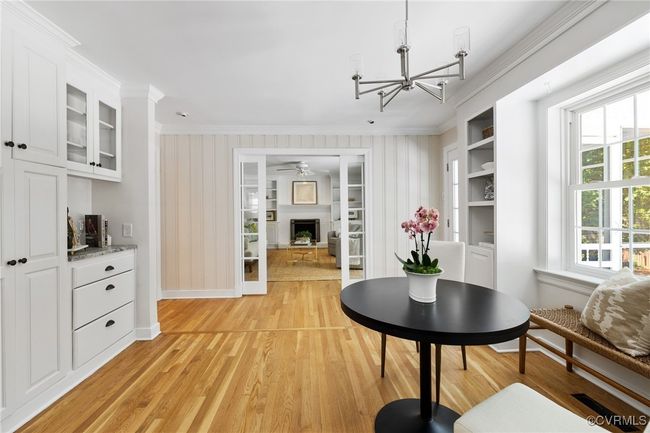 Eat-in area of kitchen featuring ornamental molding, lots of natural light, hardwood floors, pantry, bar area and built-in cabinets and shelving. | Image 16