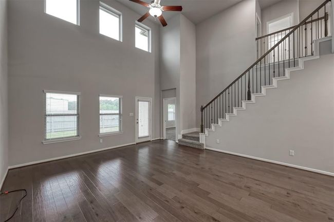The family area's high ceiling and large windows create an inviting atmosphere, complemented by the sleek wooden floors and elegant staircase design.... | Image 10