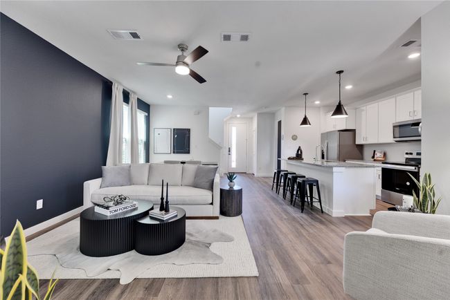 Living area featuring light wood finished floors, baseboards, and visible vents | Image 4