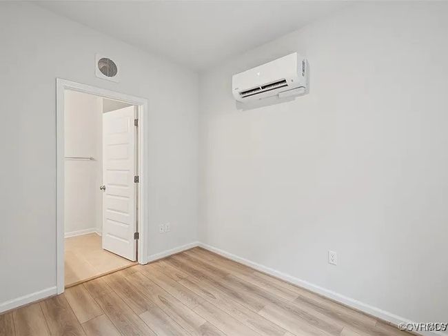 Unfurnished bedroom featuring a wall mounted air conditioner and light wood-style flooring | Image 8