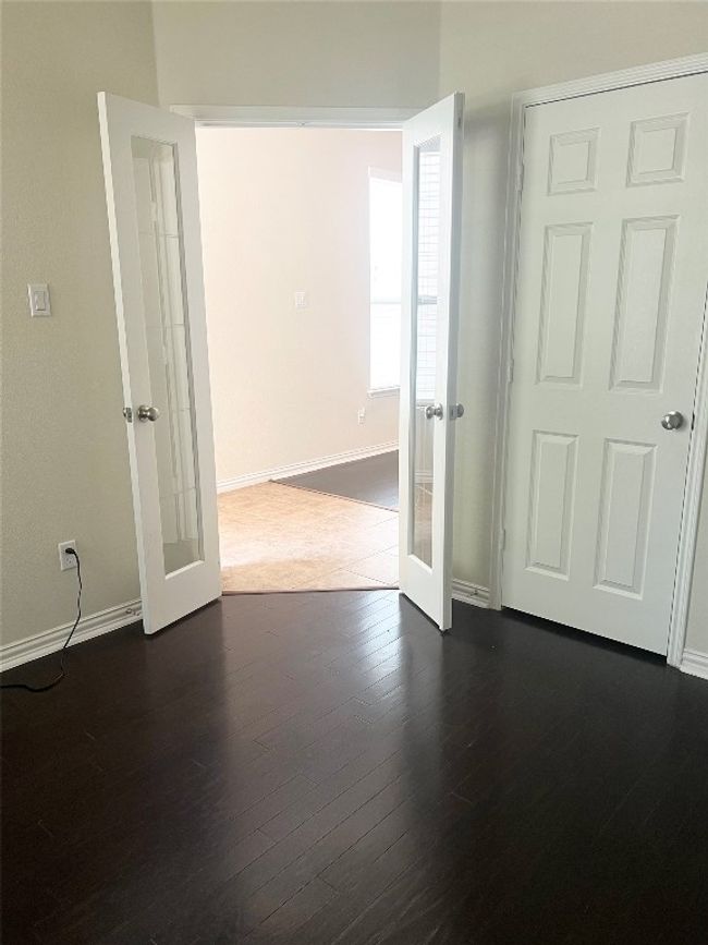 Empty room featuring french doors, baseboards, and dark wood finished floors | Image 7