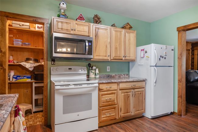 Kitchen featuring white appliances, light countertops, light brown cabinetry, and dark wood-style floors | Image 39