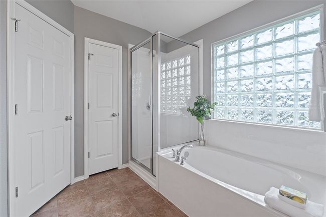 Bathroom featuring a stall shower, a bath, and healthy amount of natural light | Image 31