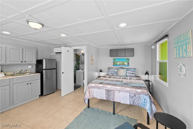 Tiled bedroom with coffered ceiling, ensuite bath, a wall unit AC, stainless steel refrigerator, and sink | Image 37