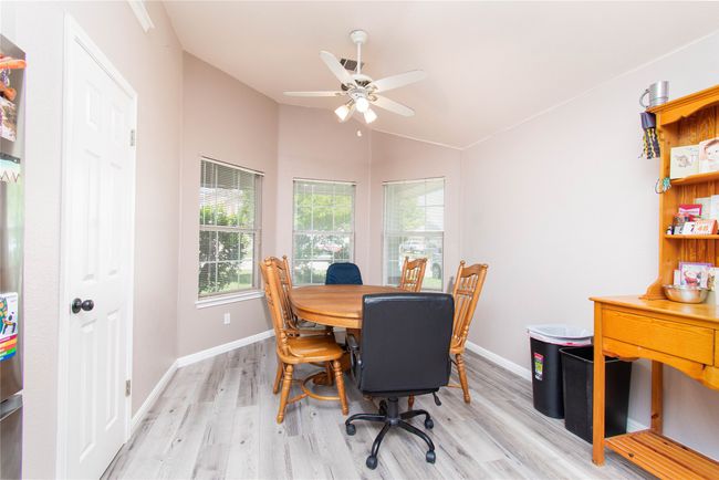 Office space featuring light wood finished floors, ceiling fan, baseboards, and lofted ceiling | Image 8