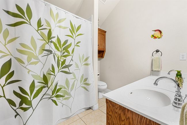 Full bathroom with tile patterned flooring, toilet, vanity, and curtained shower | Image 24