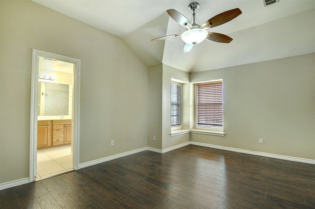 Unfurnished bedroom with lofted ceiling, ensuite bathroom, sink, dark hardwood / wood-style floors, and ceiling fan | Image 12