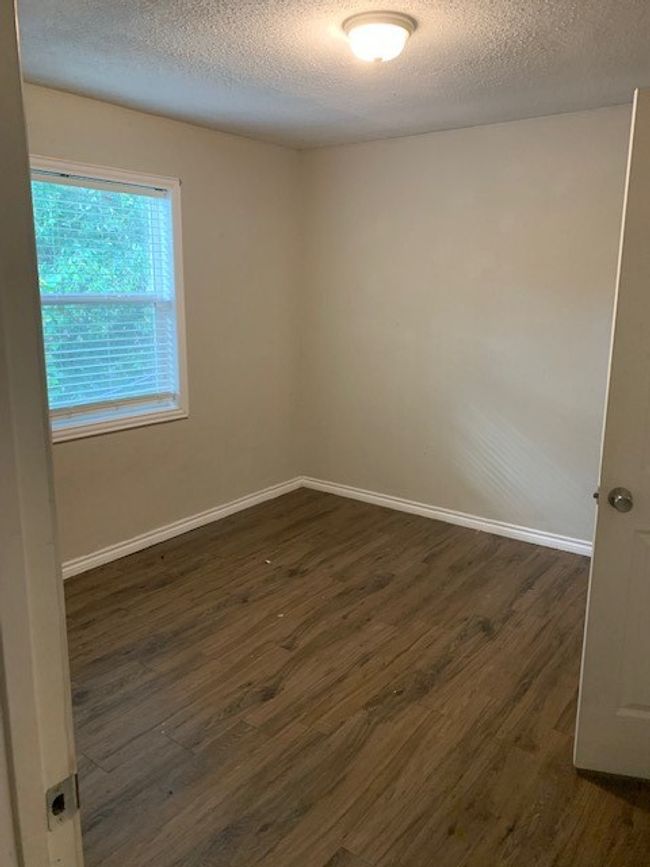 Empty room with dark wood finished floors, a textured ceiling, and baseboards | Image 9